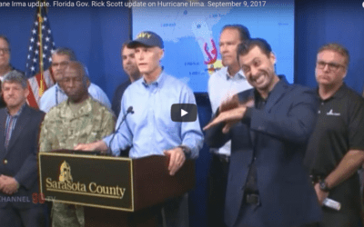 Is the sign interpreter on the right questioning Rick Scott’s ban on the terms of climate change & global warming?