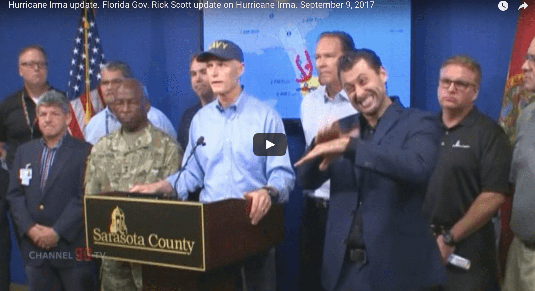 Is the sign interpreter on the right questioning Rick Scott’s ban on the terms of climate change & global warming?